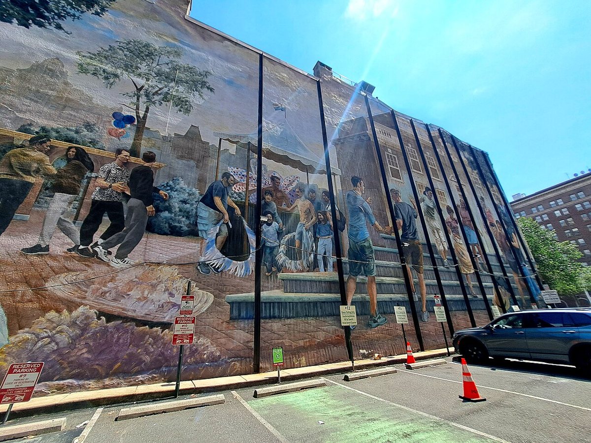 A large outdoor mural on the side of a Philadelphia rowhouse